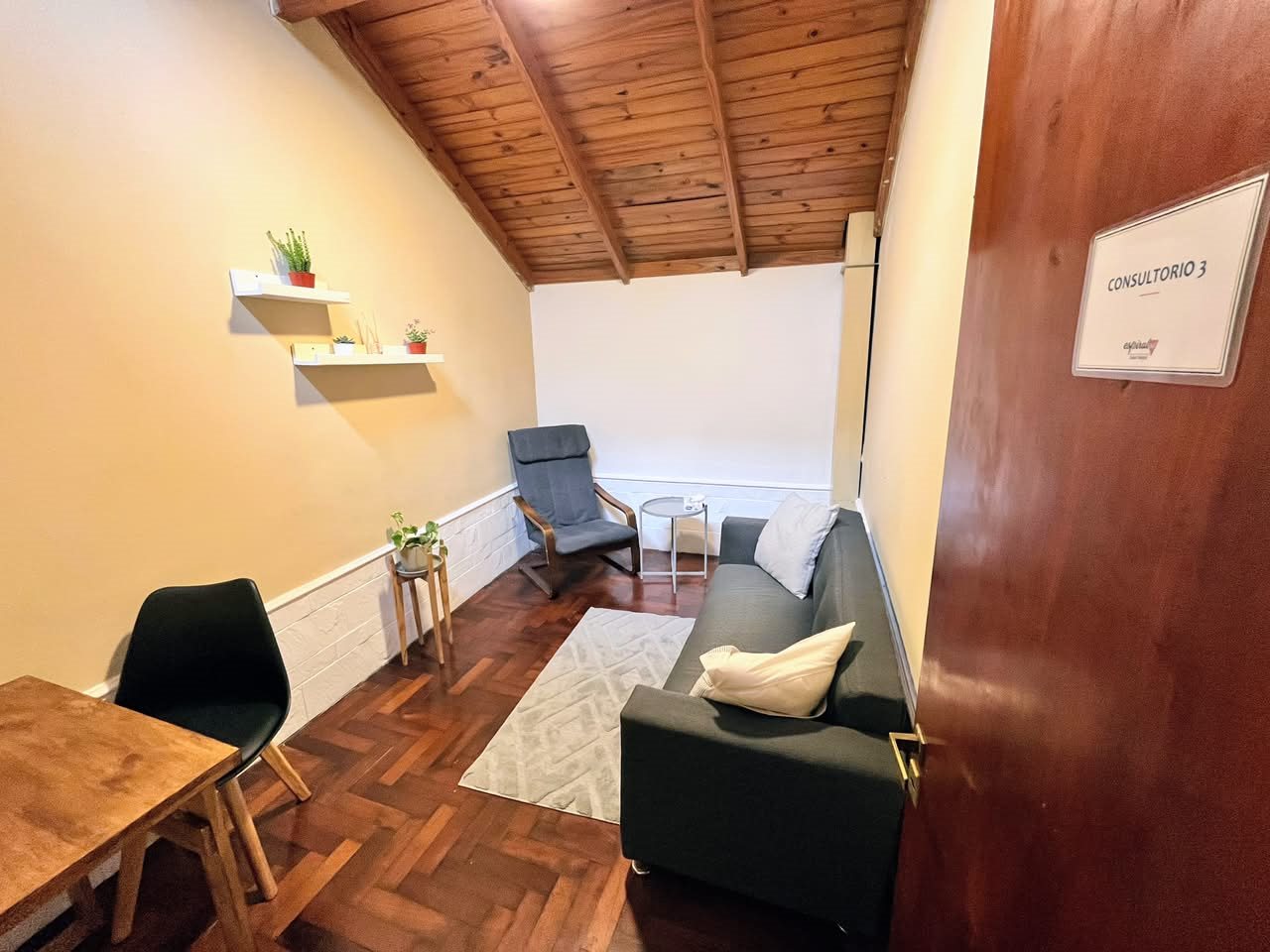 Consultorio 3 de Espiral Sur, con techo de madera, sillón y escritorio